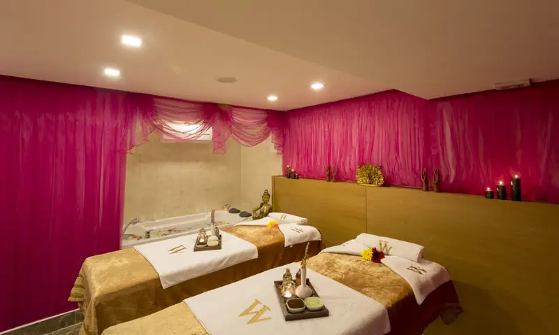 Ein Behandlungsraum im Spa, mit zwei mit Handtüchern vorbereiteten Massageliegen und einer Wanne an der Rückwand.
